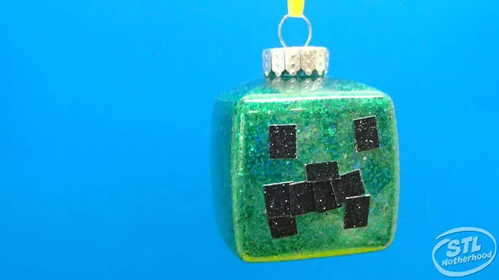 square Christmas ornament with green glitter and black glitter stickers to look like a Minecraft Creeper face