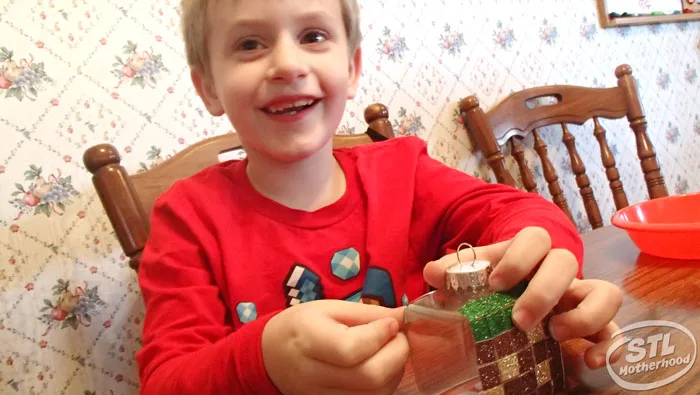 young boy in red shirt making a minecraft grass block Christmas ornament 