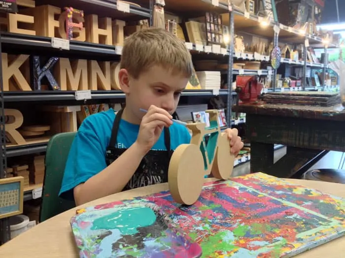 kid painting wooden bike at yucandu art studio