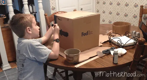 young boy at table making the enderman costume head from a box