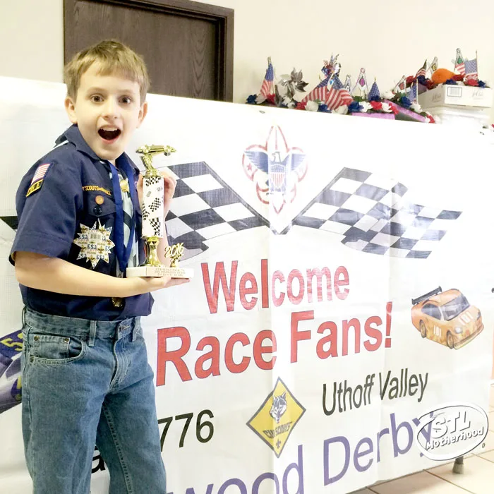 Cub Scout with a pinewood derby trophy