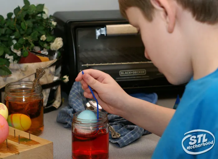 kid double dipping eggs in dye