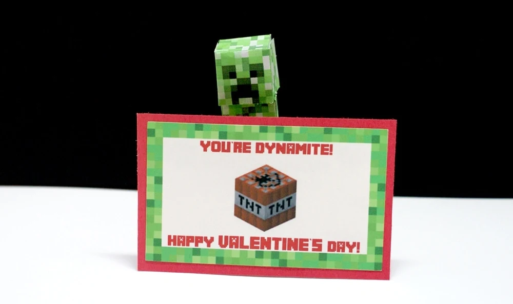 Paper Minecraft creeper holding a Valentine card that says "you're dynamite"