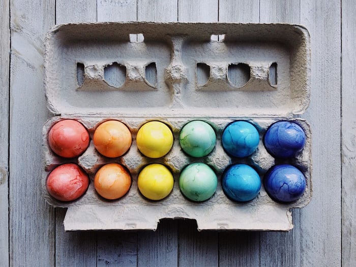 a dozen dyed easter eggs in a carton