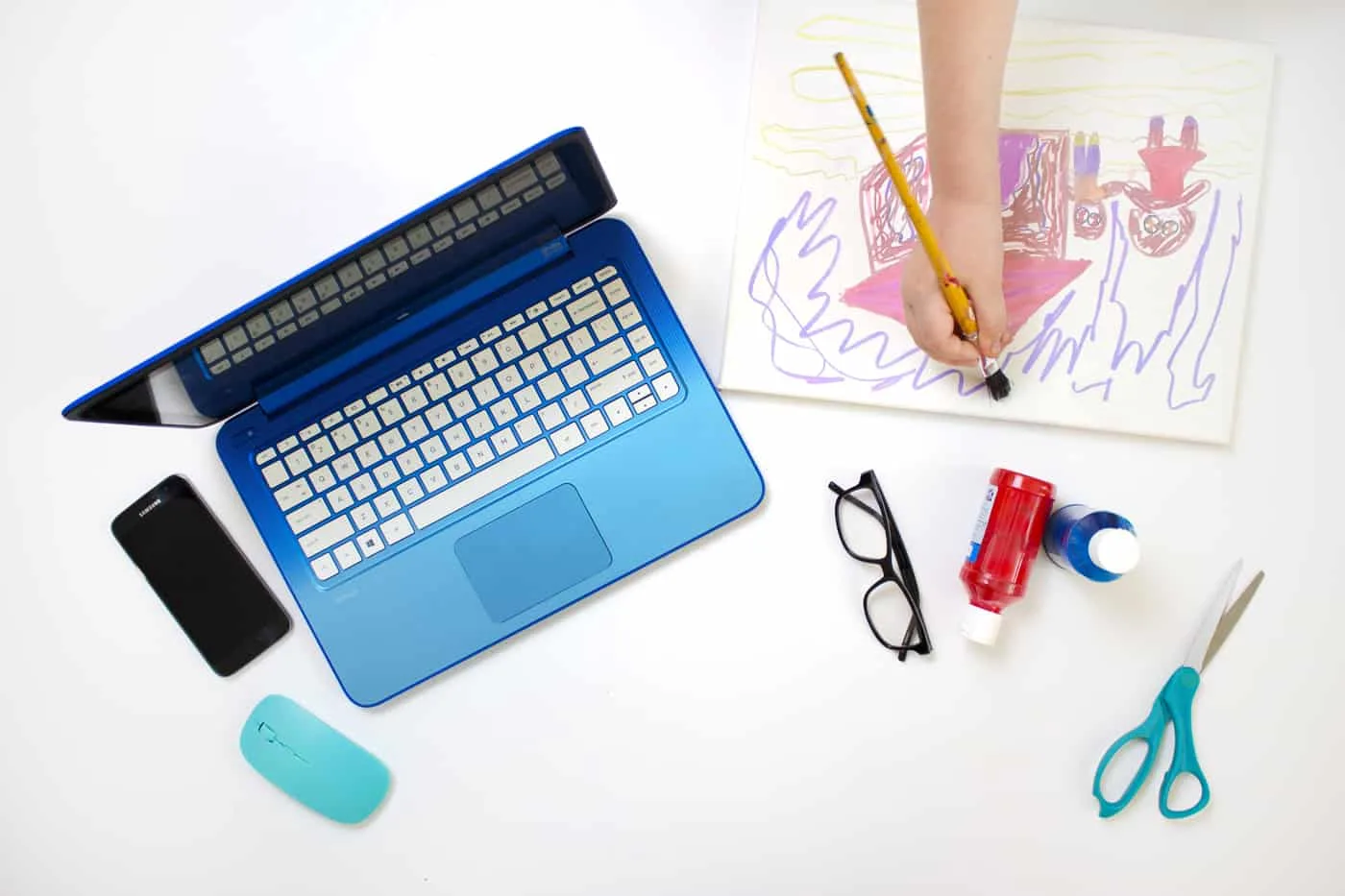 kid doing art next to lap top