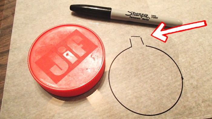 peanut butter lid being used as template to draw a circle