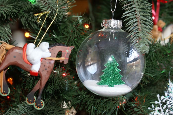 glass christmas ornament with green foam sticker tree and salt for the ground, hanging on a Christmas tree.