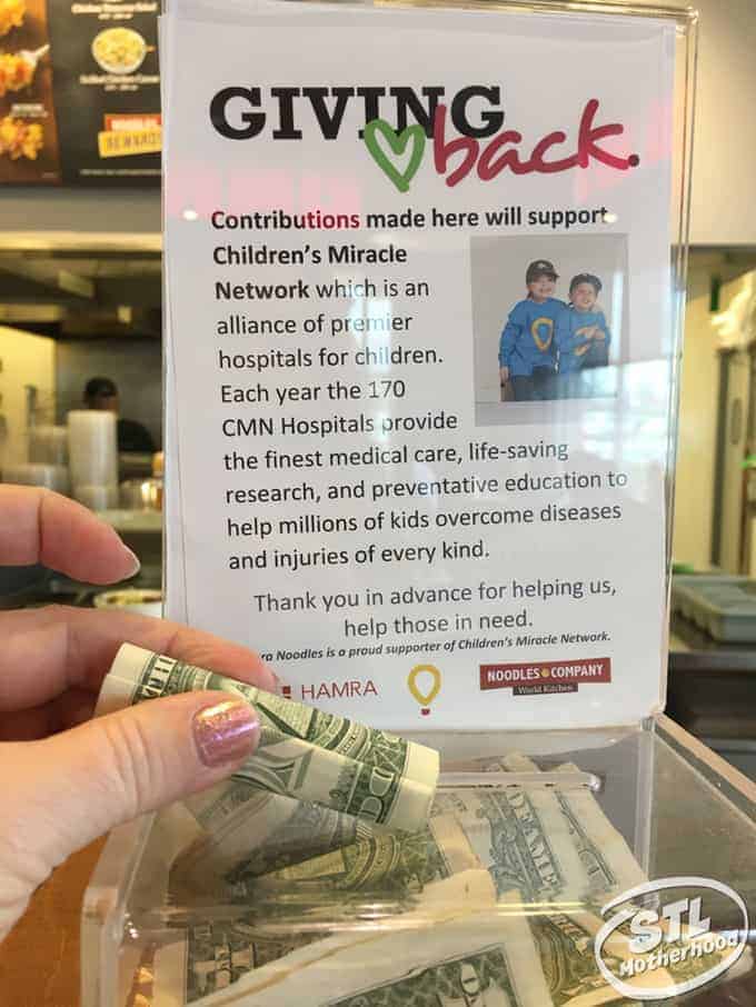 hand placing money in donation box for Children's Miracle Network