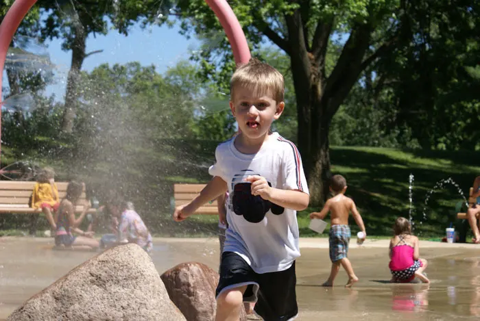 Preschool boy running through splash fountain at a St. Louis County Park