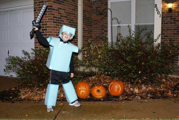 Child dressed in Minecraft costume for Halloween, foam armor plate, helmet and leggings. He is standing by jack-o-lanterns.