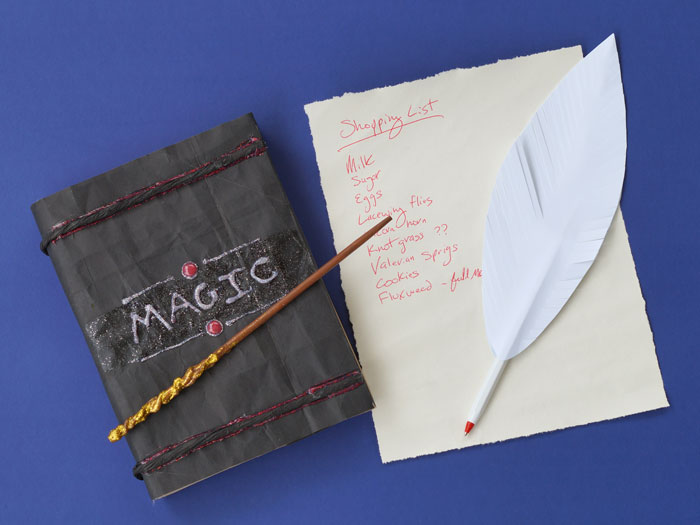 Spell book with magic wand, a quill and grocery list.