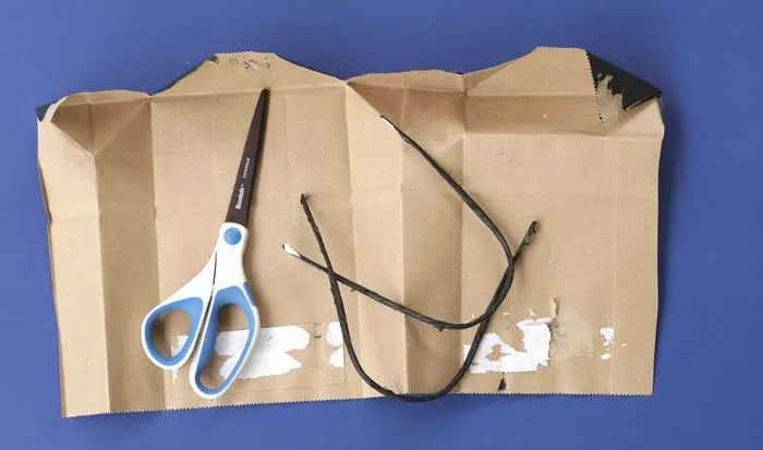 cutting up a gift bag to make a book cover with scissors
