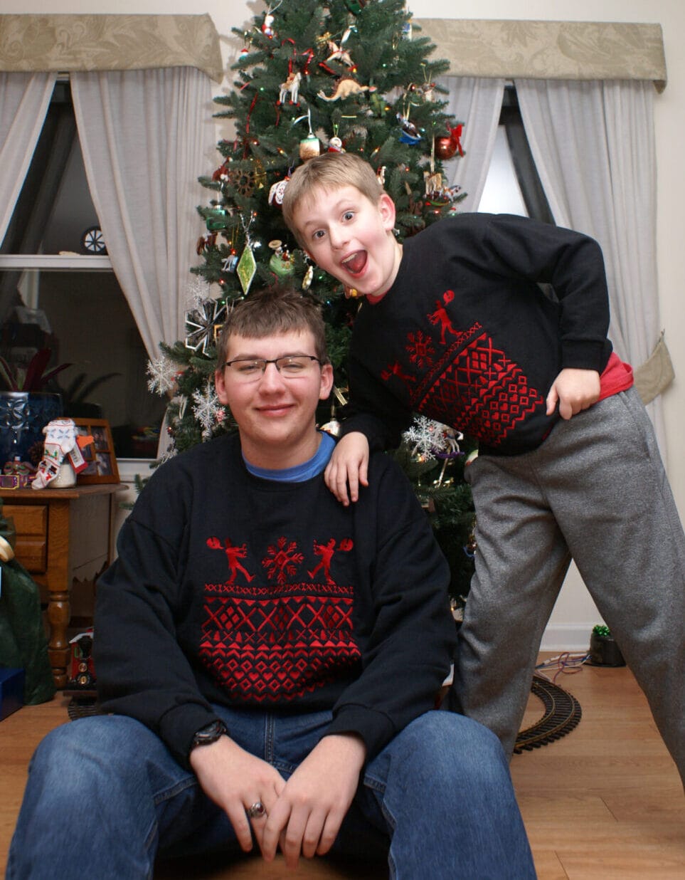 brothers in matching christmas zombie sweaters by a Christmas tree