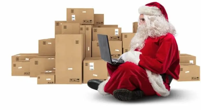 Santa Claus sitting with laptop and with Christmas boxes around