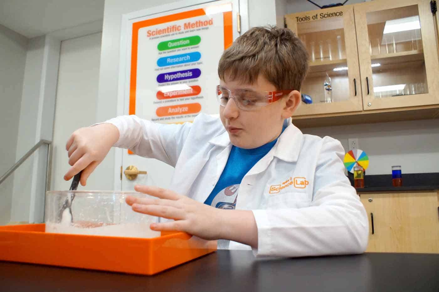 kid in lab coat doing STEAM activities at the Magic House lab