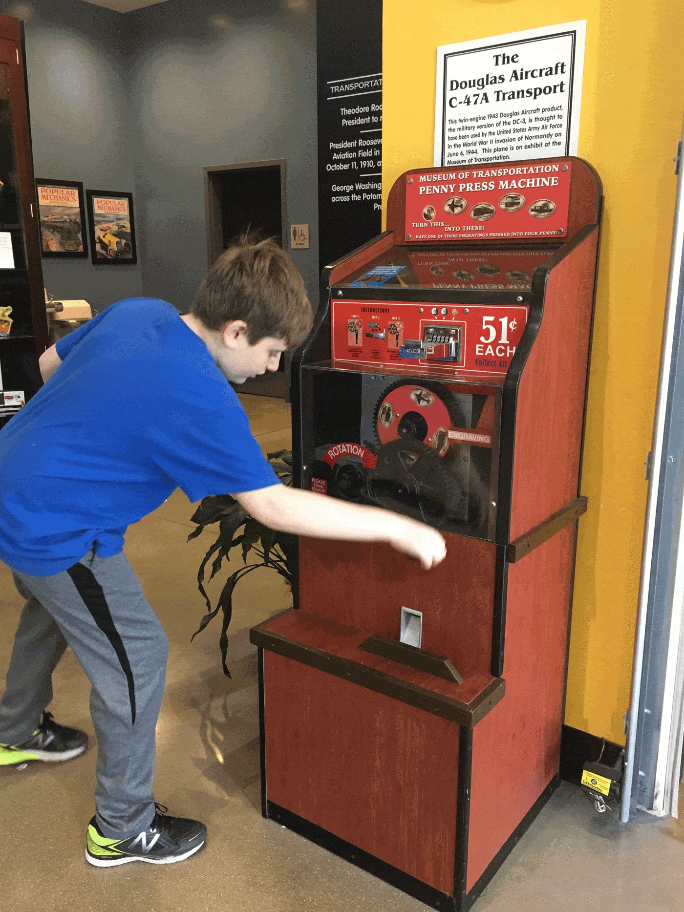 Kid making a smashed penny, turning crank on the machine.