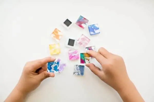 Hand of child holding colorful glass tile magnets