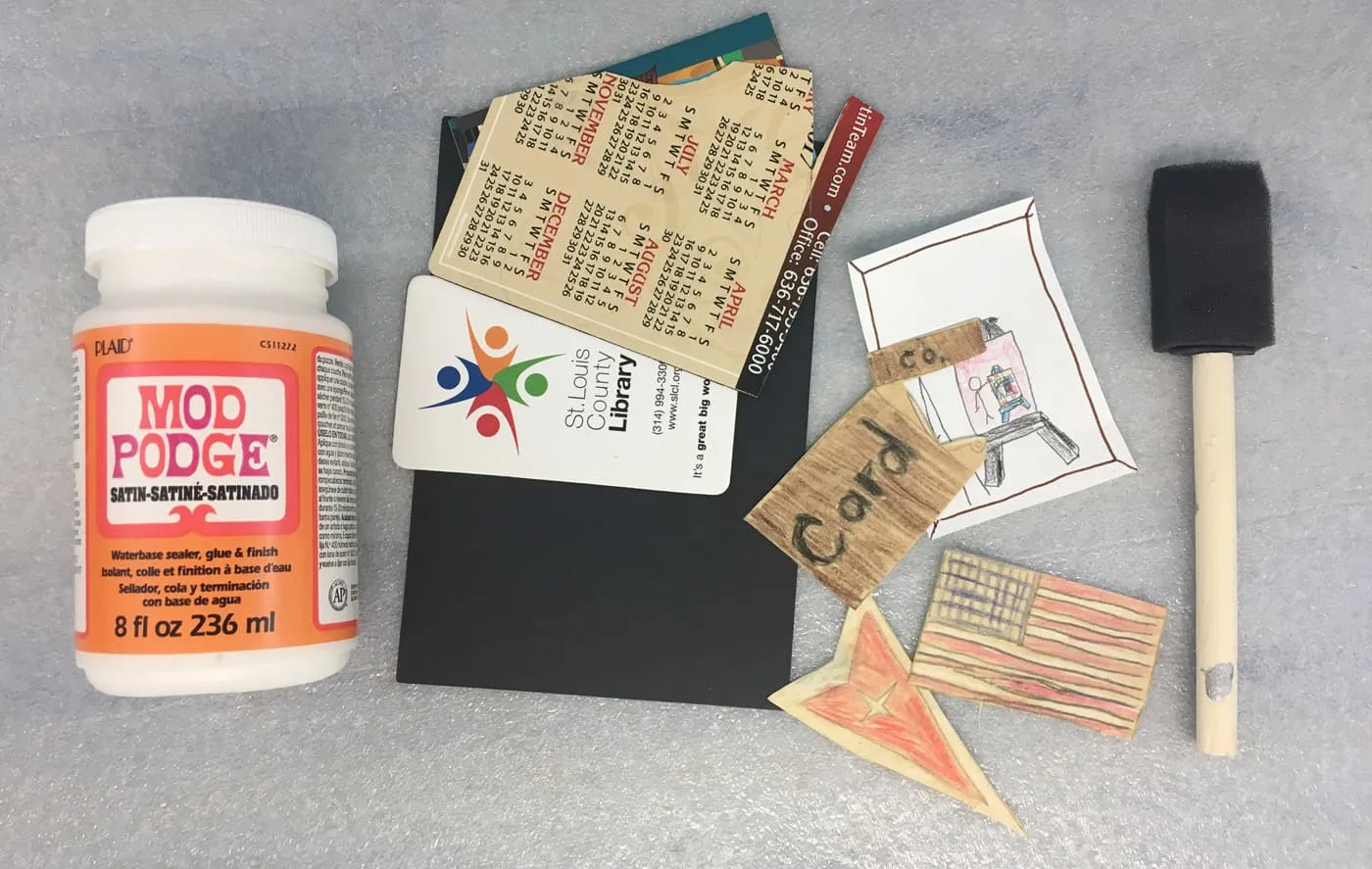 supplies for making decoupage art: mod podge, old sheet magnets, foam brush and kid drawings or doodles.