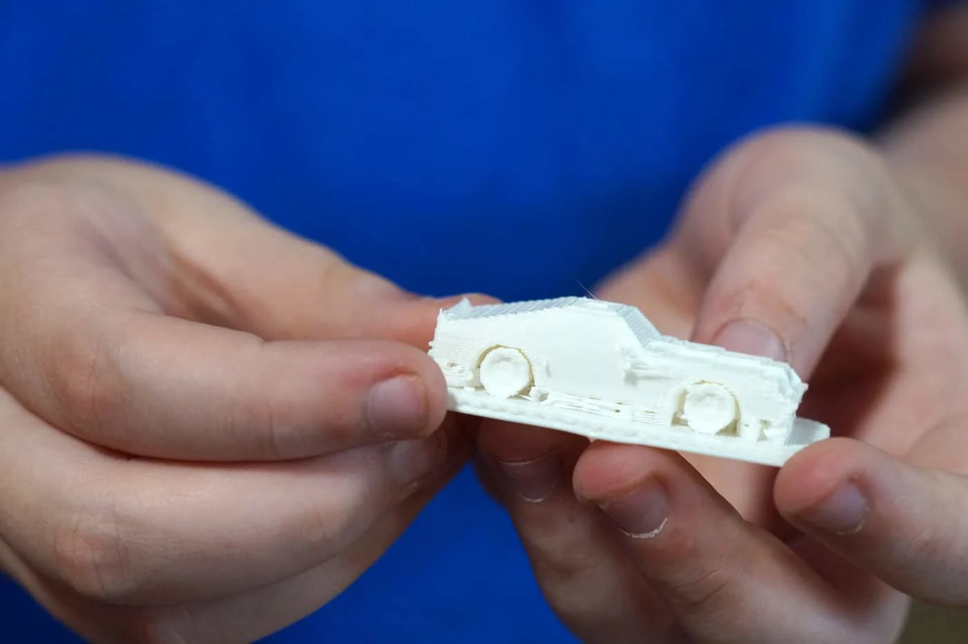 white plastic 3D printout of a car in kid's hands.