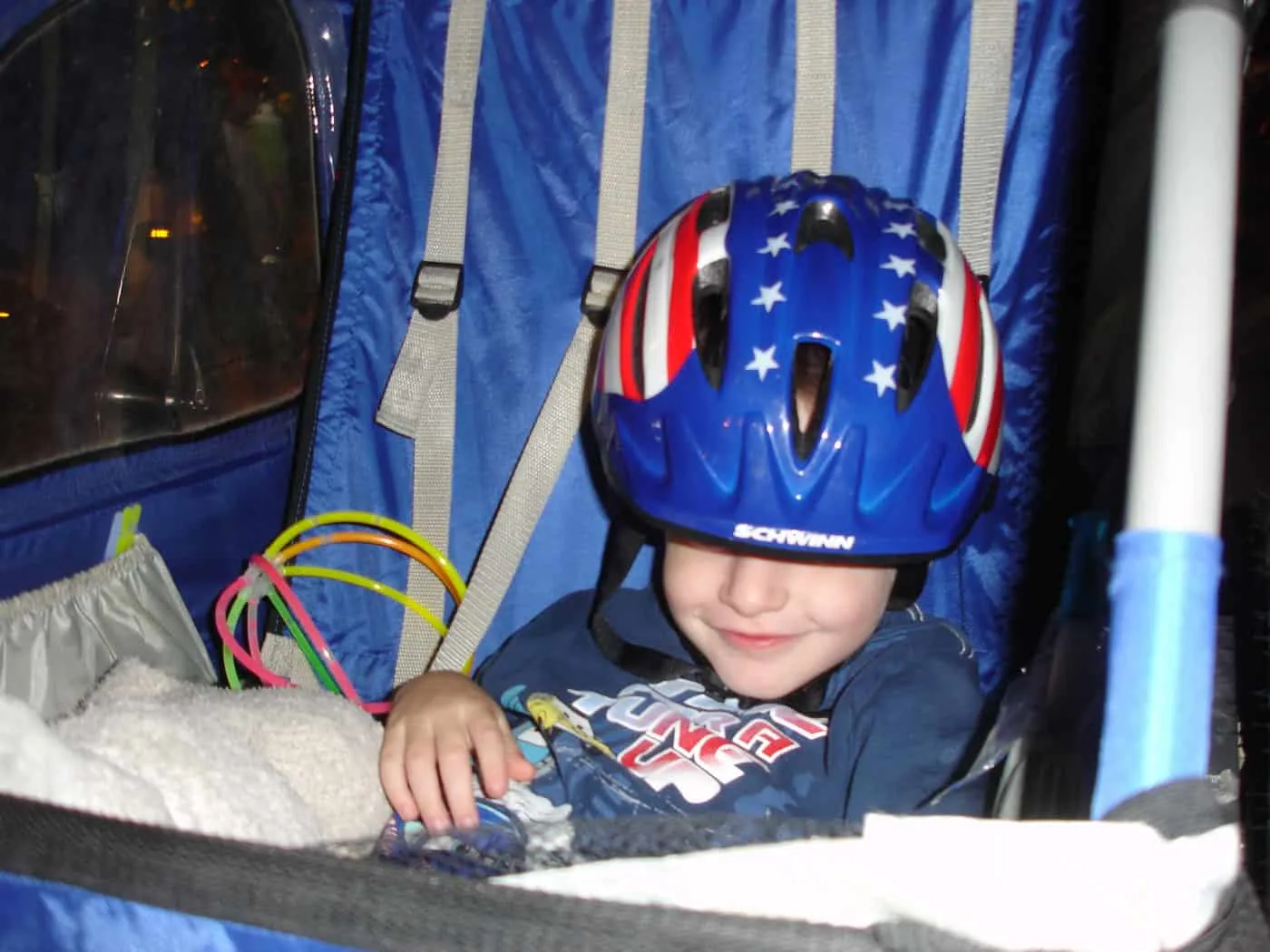 toddler with stars and stripes bike helmet sitting in bike trailer