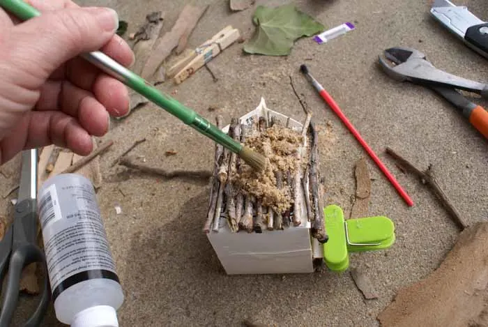 brushing sand into the space between sticks