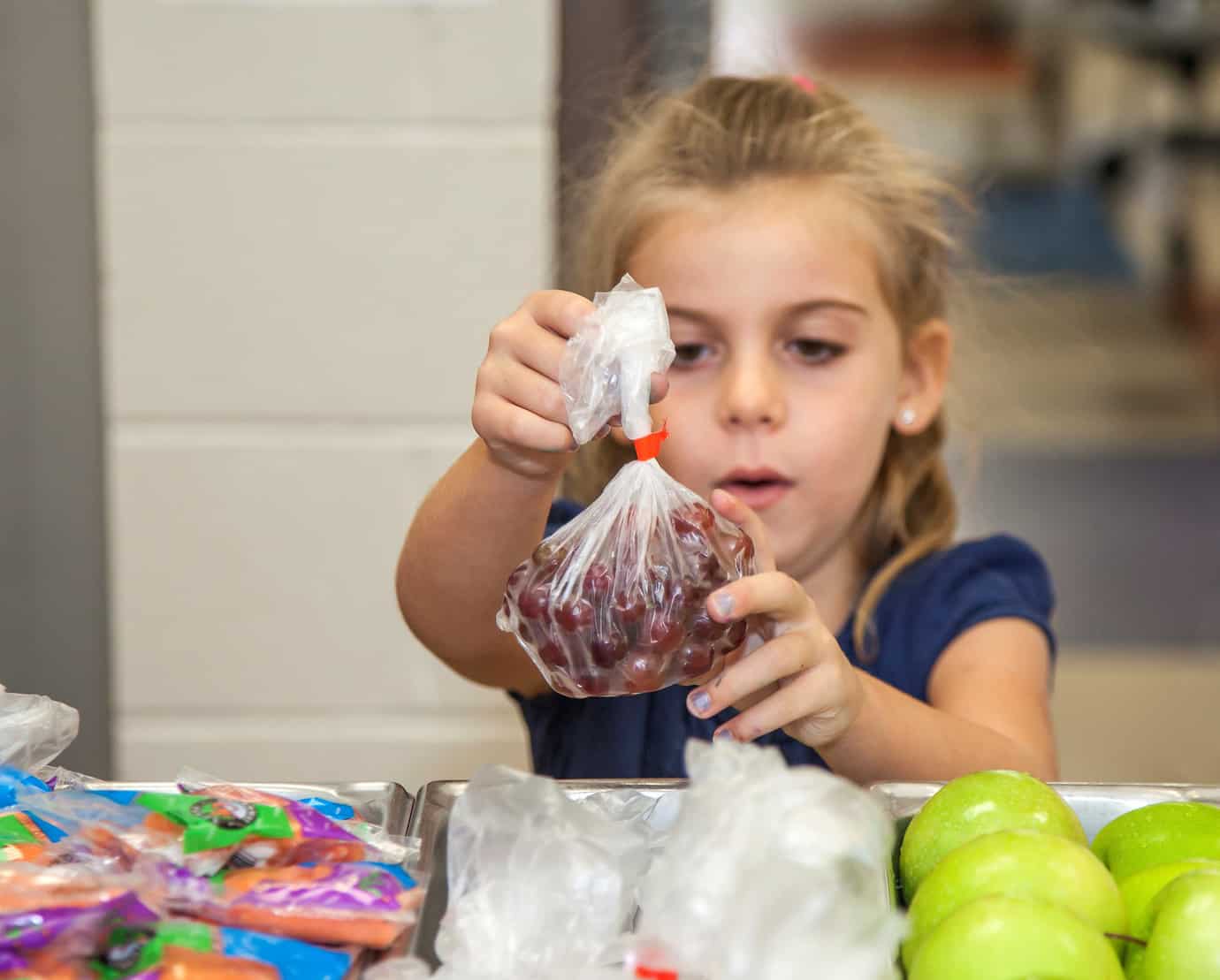 Child selects grapes from a school lunch line