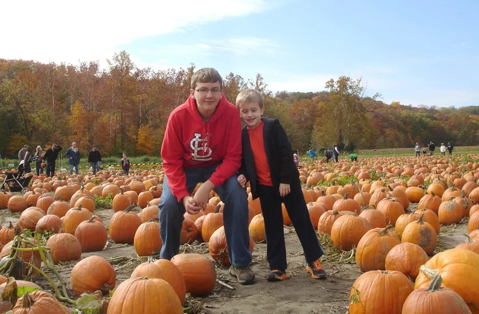 two brothers in a pumpkin field in St. Louis. One is wearing a Cardinals shirt