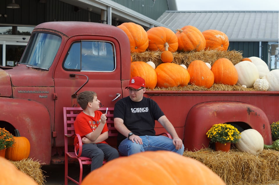 Two brothers in front of a classic red pickup full of pumpkins at Eckert's pick your own pumpkin patch in the St. Louis Area