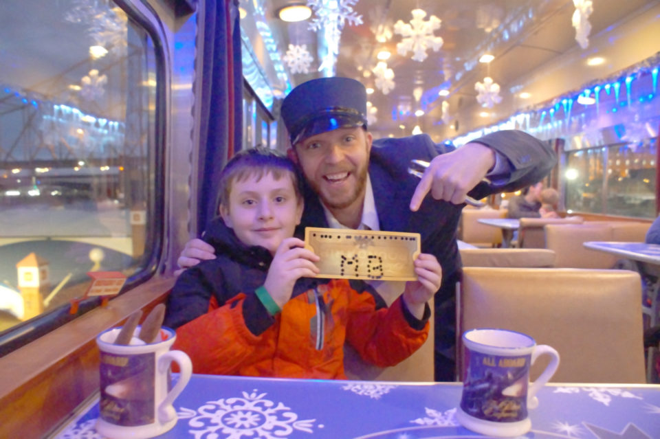 Boy in red coat with a Golden Polar Express Ticket and Mr. Conductor