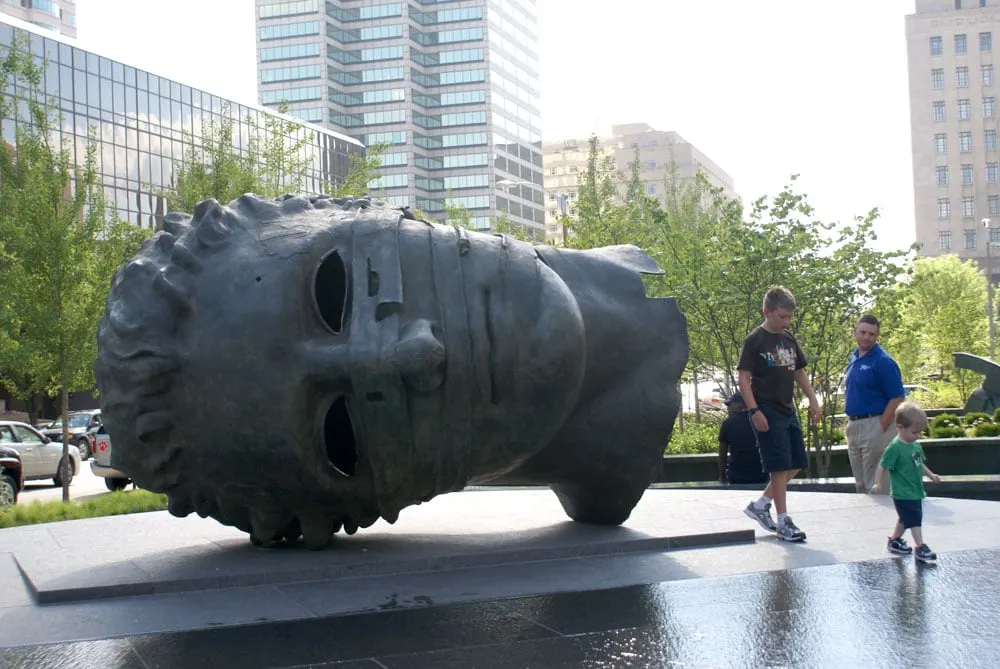 Family visiting City Garden with giant steel statue of a head