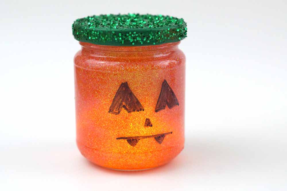 jar with glass painted to look like a pumpkin, green glitter on the lid