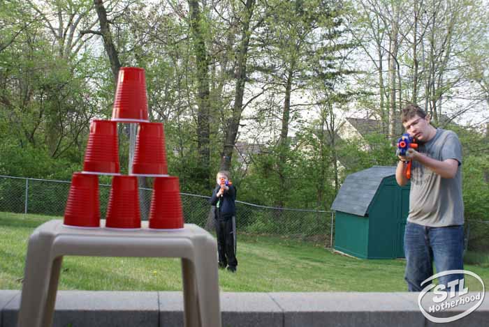 Kids playing with Nerf blasters and plastic cup targets