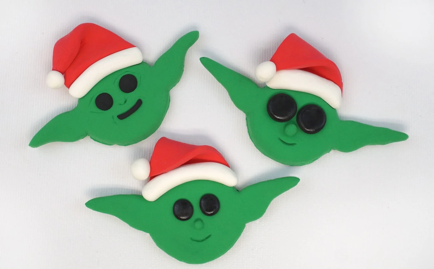 Three baby Yoda Christmas ornaments wearing Santa hats