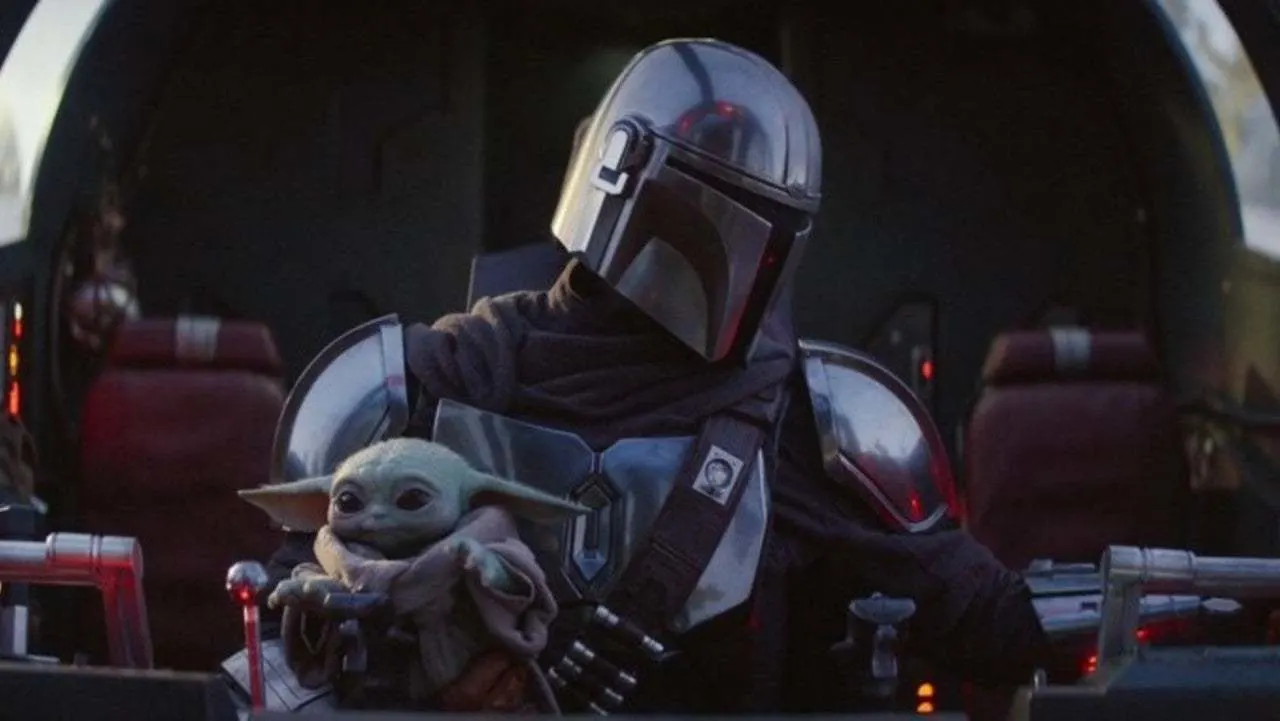 the Mandalorian and baby Yoda, with baby reaching for the ships controls