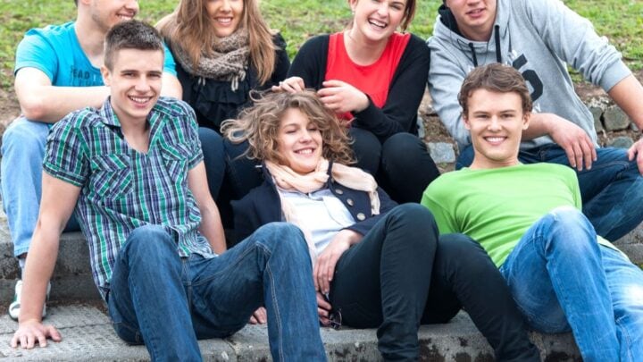 group of teens sitting on sidewalk