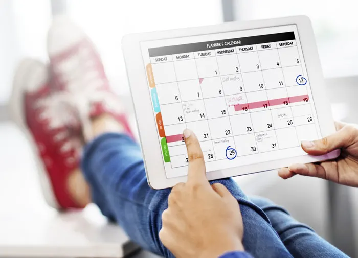 calendar on an ipad, feet up on a desk