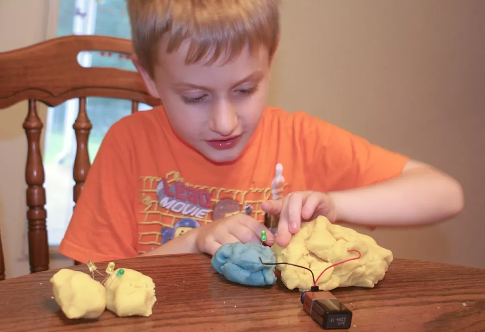 kid playing with electric play dough and making a circuit with LED lights