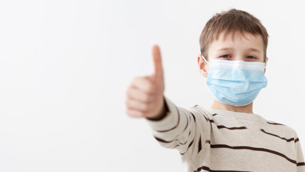 boy in tan shirt wearing a blue disposable mask