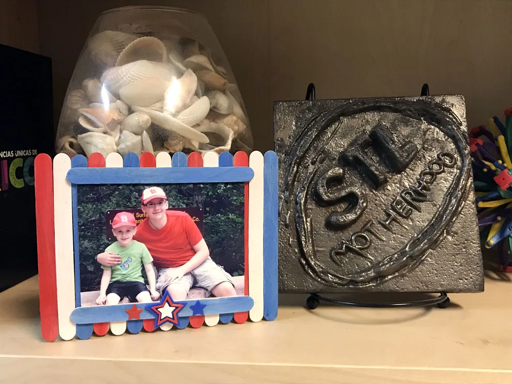 Red, white and blue craft stick photo frame on display on a shelf.