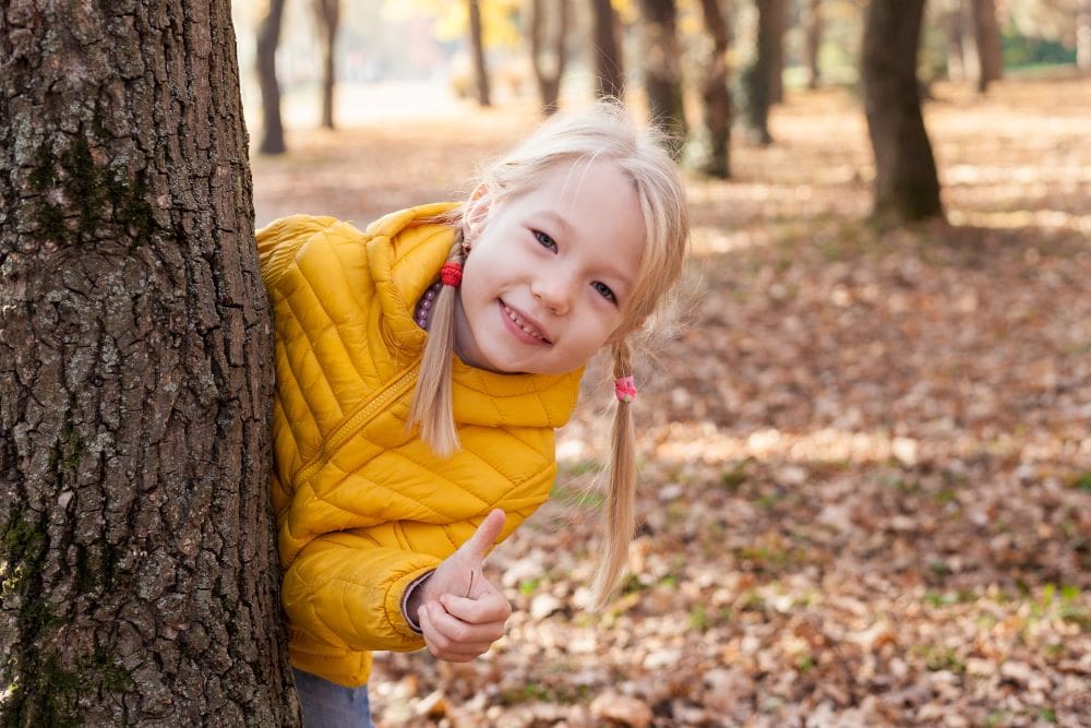 girl in yellow outside by a tree in the autumn