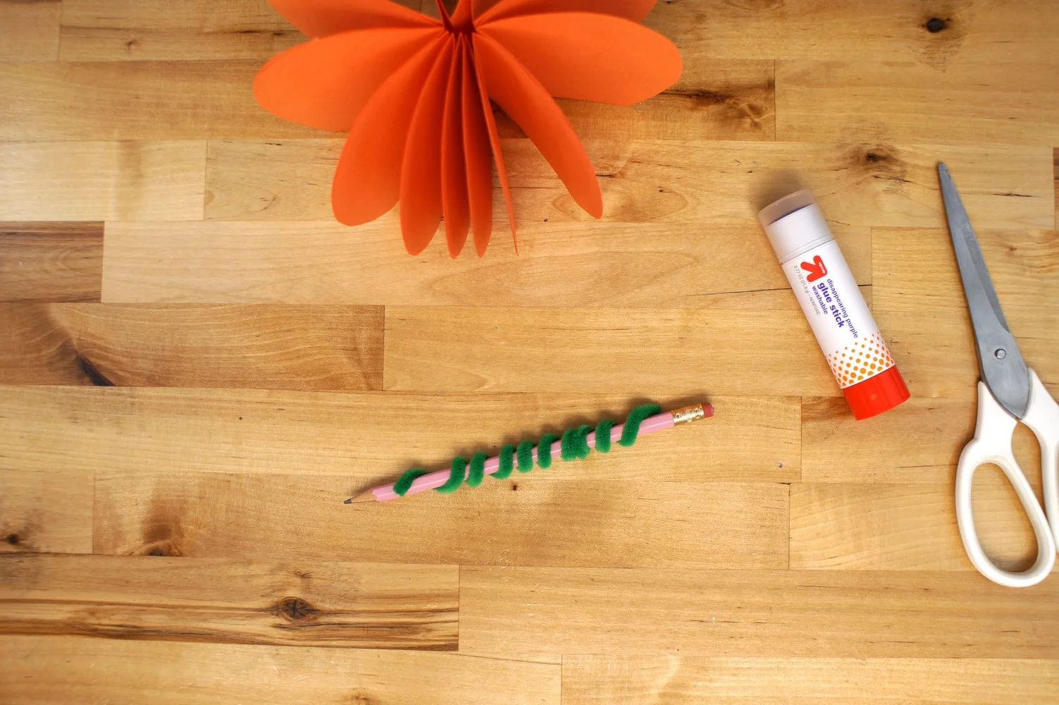 curl a green fuzzy stick around a pencil to form the stem of the pumpkin