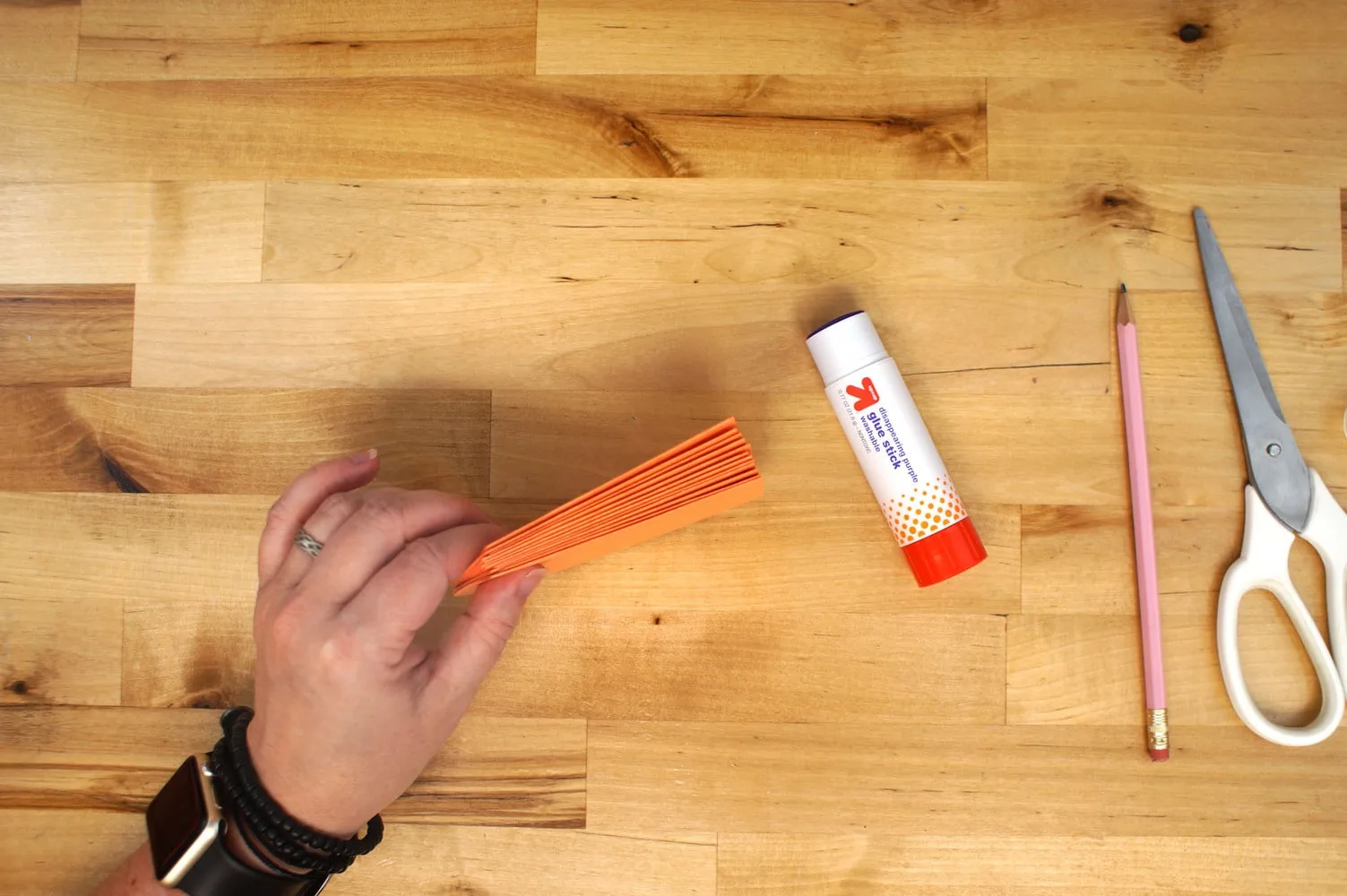 hand holding a stack of orange paper pumpkin slices together for gluing