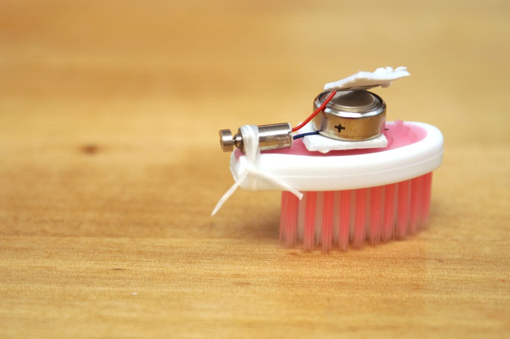 pink brush bot with motor tied to handle using string