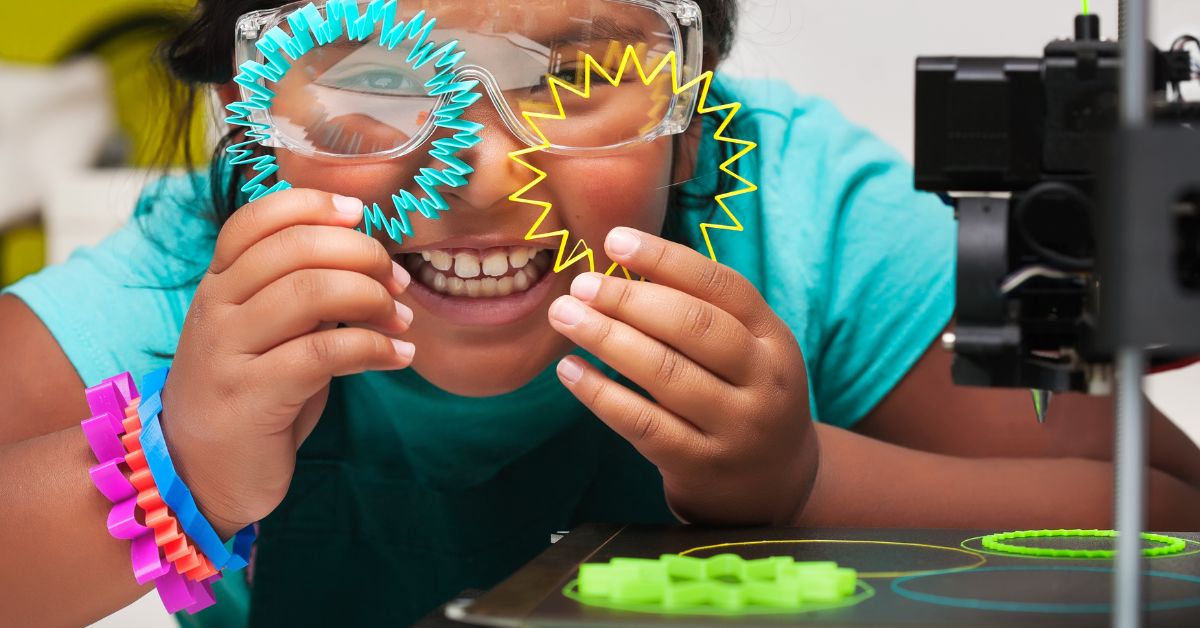 A young student wearing safety glasses sitting next to a 3D printer. She's holding up two 3D prints to her eyes.