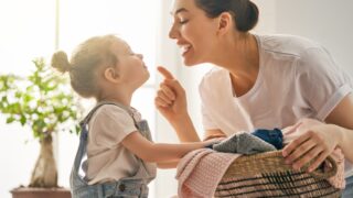 A woman and her small child are looking at each other, face to face. The mother is carrying a basket.