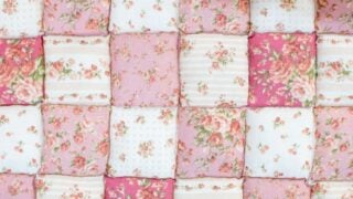 Close-up of a pink puff quilt featuring rose-print fabric squares, delicate floral patterns, and pale stripes.